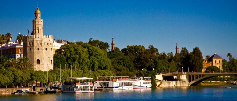 El Puente de San Telmo y la Torre del Oro, a orillas del Guadalquivir, al atardecer.