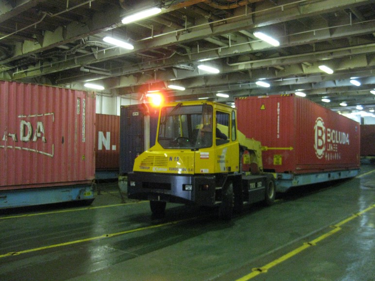 Los estibadores sevillanos estiban los contenedores sobre sus plataformas en la bodega principal del barco.